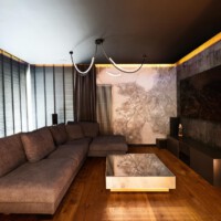 Nowoczesny salon zrealizowany przez Ardeko – narożna sofa, tapety Wallart i Elitis, zasłony Ridex, drewniane żaluzje z napędem Somfy, elegancka aranżacja w ciemnych tonacjach